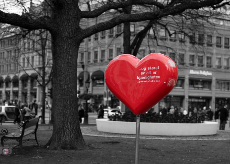 Rotes Herz mit der Aufschrift „Doch das Größte ist die Liebe“ an grauer Stadtmauer in Oslo.