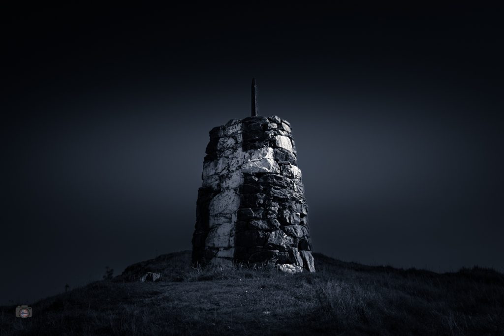 Dunkles FineArt Foto eines alten Denkmals an den Atlantikbrücken, steinerner Turm vor fast schwarzem Himmel, Teil der Serie „Dystopisch“