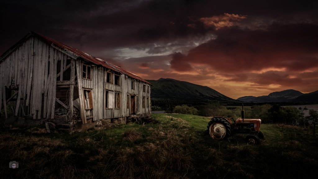 Verlassenes Haus mit altem Traktor in Norwegen, dramatisch bearbeitet, unter schwerem Himmel als Symbol für Vergänglichkeit und stille Geschichten.