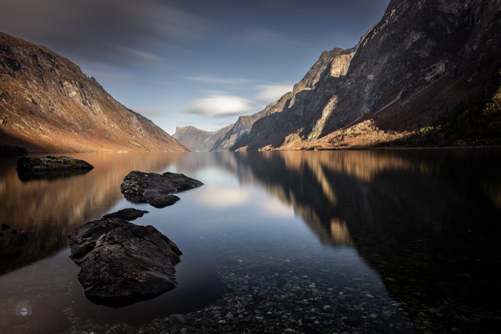 Bergsee in Norwegen im Herbstlicht mit ruhigem Wasser und sanfter Spiegelung der Berge.