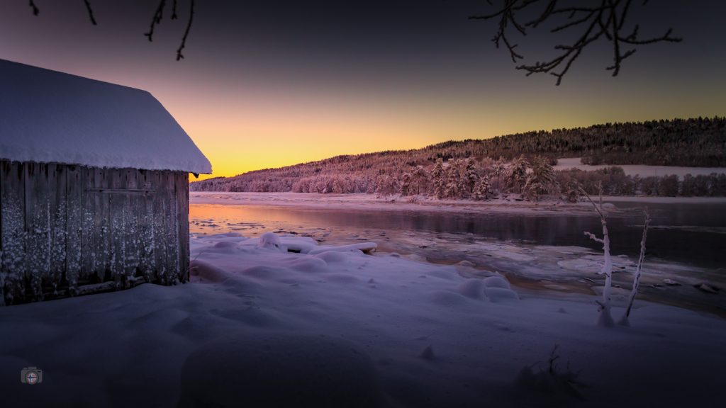 Winterlandschaft mit stiller Wasserfläche und sanftem Morgenlicht. Die Sonne kehrt langsam zurück und symbolisiert einen leisen Neuanfang im neuen Jahr.