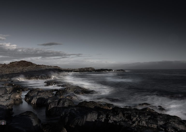 FineArt Langzeitbelichtung einer felsigen Atlantikküste mit ruhigem Wasser, dunklen Felsen und leerem Himmel.