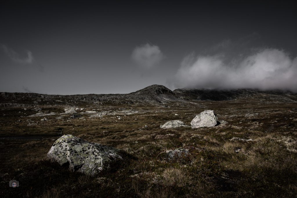 Helle Felsen in einer kargen Berglandschaft der Sunndalsfjella in Norwegen mit tiefen Wolken über den Bergen.