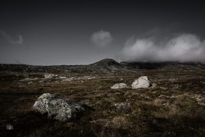 Helle Felsen in einer kargen Berglandschaft der Sunndalsfjella in Norwegen mit tiefen Wolken über den Bergen.