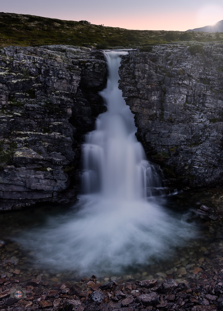 Wie ein heller Strom tritt das Wasser aus der dunklen Felswand hervor. Eingeschlossen von massivem Gestein findet es seinen Weg in die Tiefe