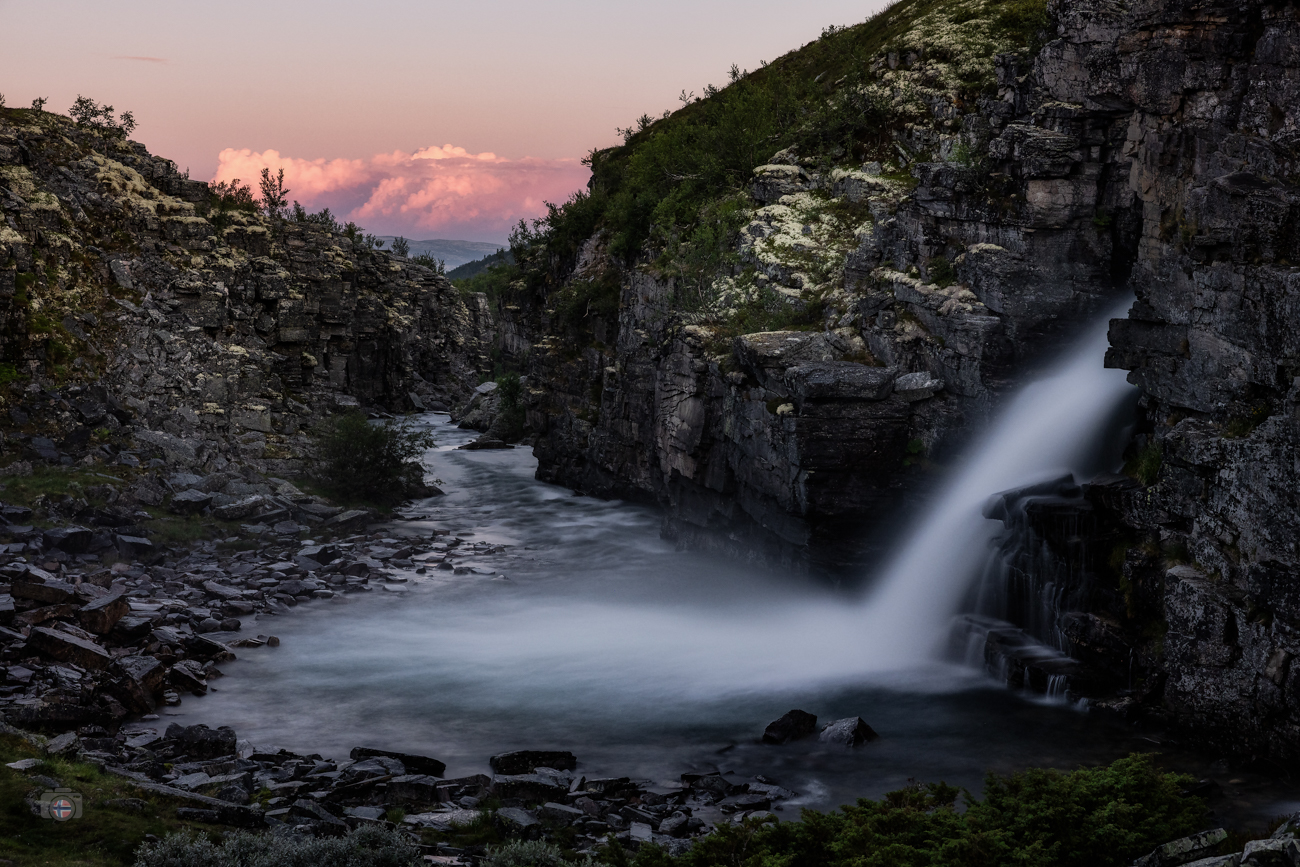 Tief zwischen den Felsen rauscht das Wasser durch die noch dunkle Landschaft. In der Ferne glüht bereits der Himmel. Zwei Welten, getrennt d