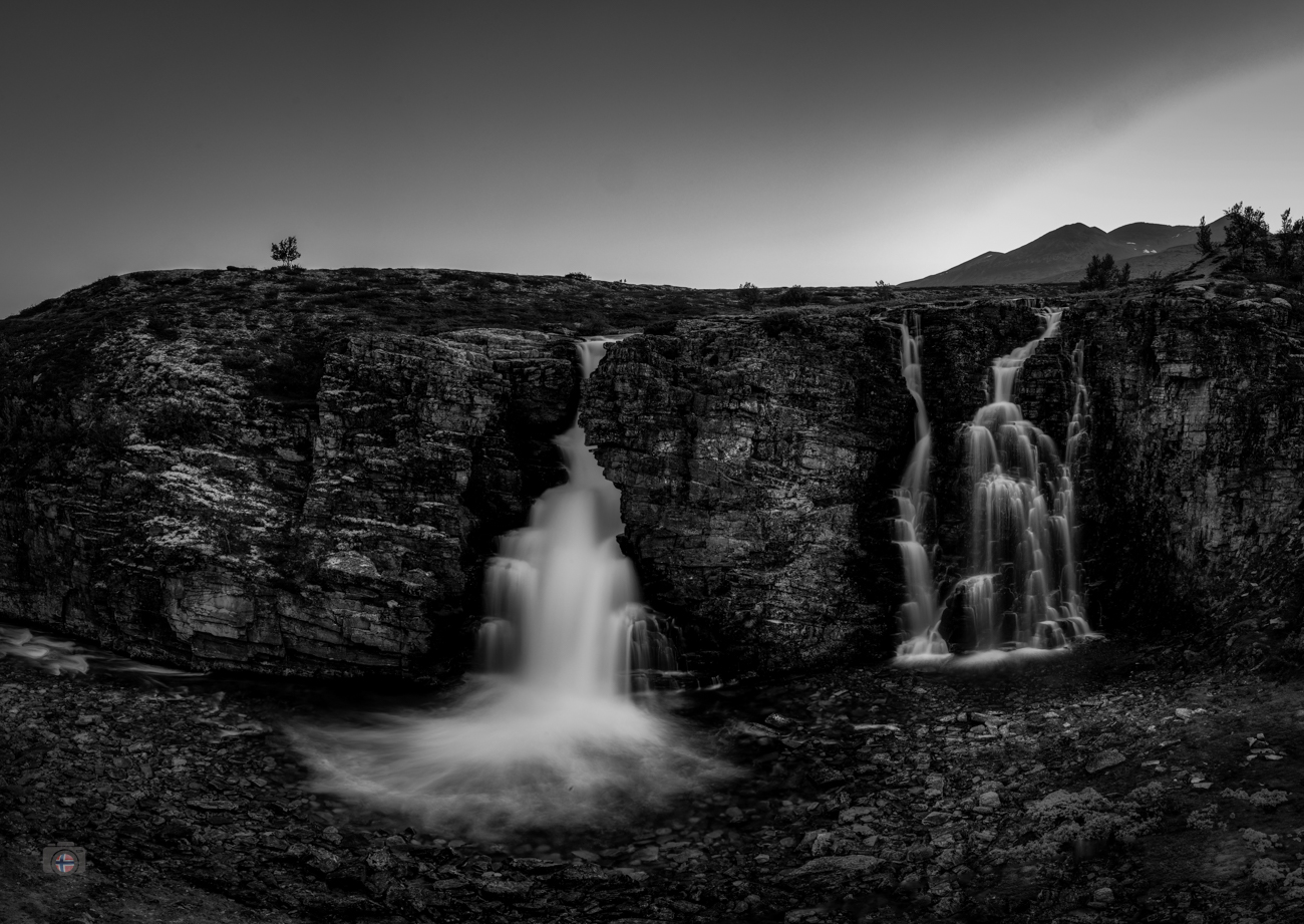 Das Wasser bricht über die dunkle Felskante und stürzt mit voller Kraft in die Tiefe. Inmitten der schweren Felsen bleibt es das einzige Ele