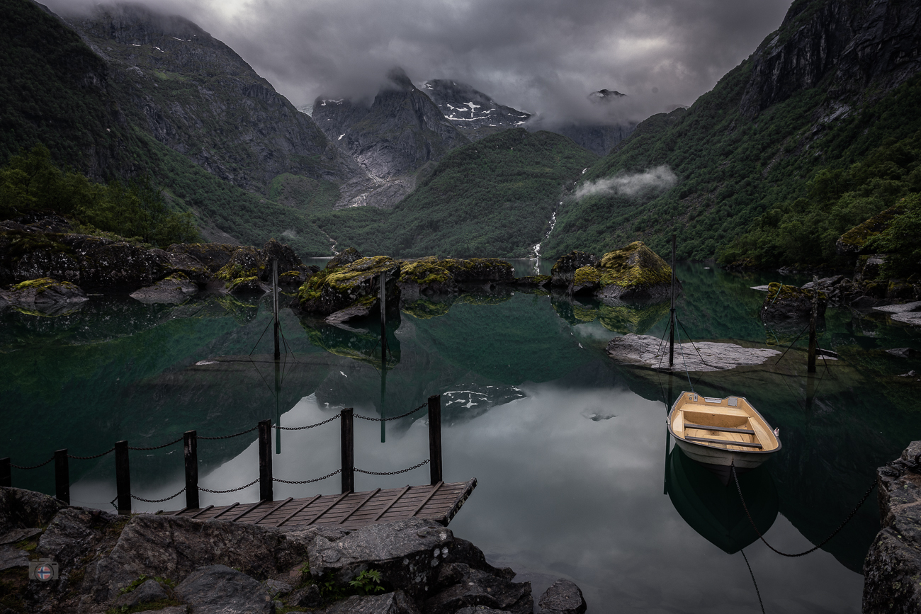 Die Wolken ziehen tief durch die Berge, während das Wasser beinahe regungslos unter ihnen liegt. Für einen Moment scheint die Landschaft lan