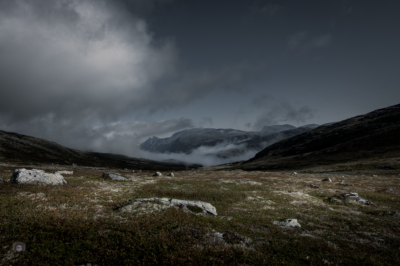 Eine weite, karge Berglandschaft in den Sunndalsfjella in Norwegen. Tief liegender Nebel verhüllt Teile der entfernten Berge und verstärkt d
